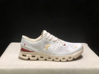 Side profile of a white On Cloud X4 sneaker with gold branding, burgundy heel detail, and cream-colored outsole.