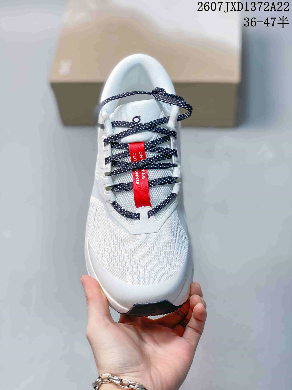 Top view of the white sneaker showing the perforated-looking upper, patterned laces, and red tongue detail.