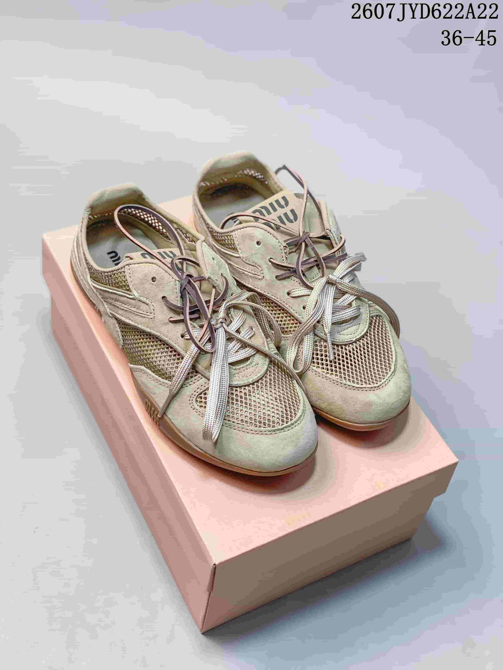 Pair of light beige Miu Miu Gymnasium low-top sneakers displayed on a pink box, with contrasting laces and gum-tone outsoles; image text shows 2607TYD622A22 and 36–45.