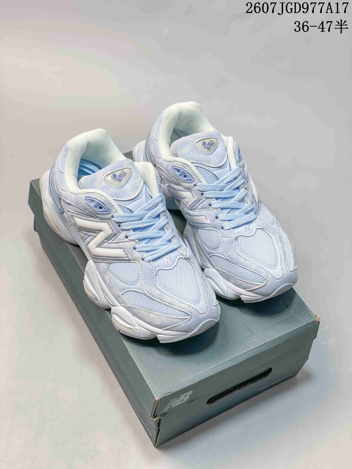 Pair of light mint and white New Balance 9060 sneakers displayed on a shoebox, showing layered panels, mesh sections and chunky soles.