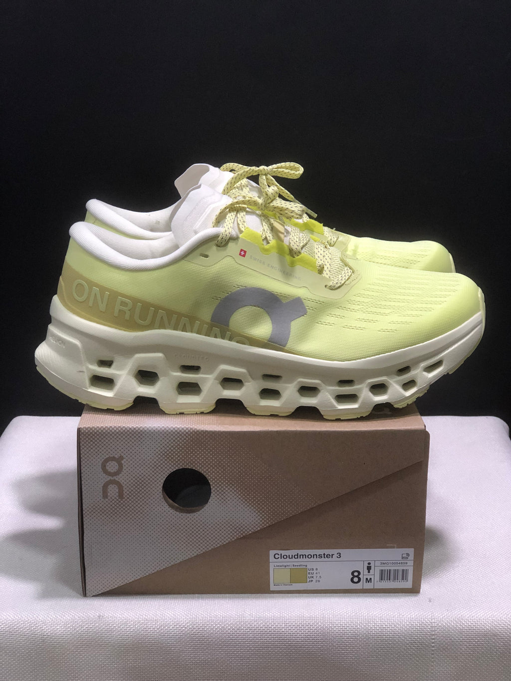 Side view of a light yellow On Cloudmonster 3 sneaker with a sculpted white midsole and product box.