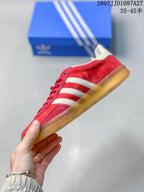 Side profile showing the red upper, white side stripes and low gum-colored sole.