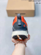 Rear view of an orange and navy ECCO sneaker showing the heel pull tab, dark heel panel, and light midsole.