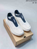 Pair of white and navy DESCENTE slip-on sneakers shown on a shoebox, with the style code and size range visible above.