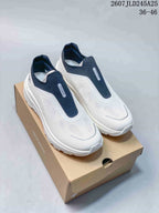 Pair of white and navy DESCENTE slip-on sneakers shown on a shoebox, with the style code and size range visible above.