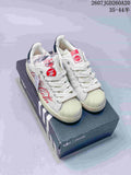 Pair of white Adidas Superstar sneakers with Coca-Cola graphics displayed on a branded shoe box.
