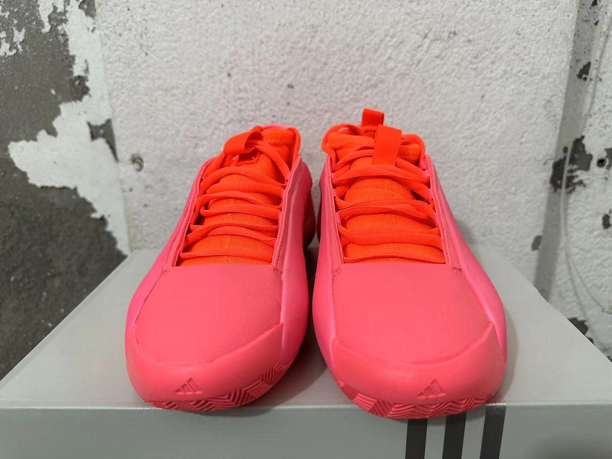 Front view of pink Adidas basketball shoes with bright orange laces and tongue