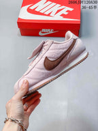 Side view of a pale pink Nike Classic Cortez sneaker with a brown side logo