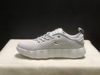 Side profile of a white sneaker showing the metallic-colored side logo, perforated upper and cushioned-looking sole.