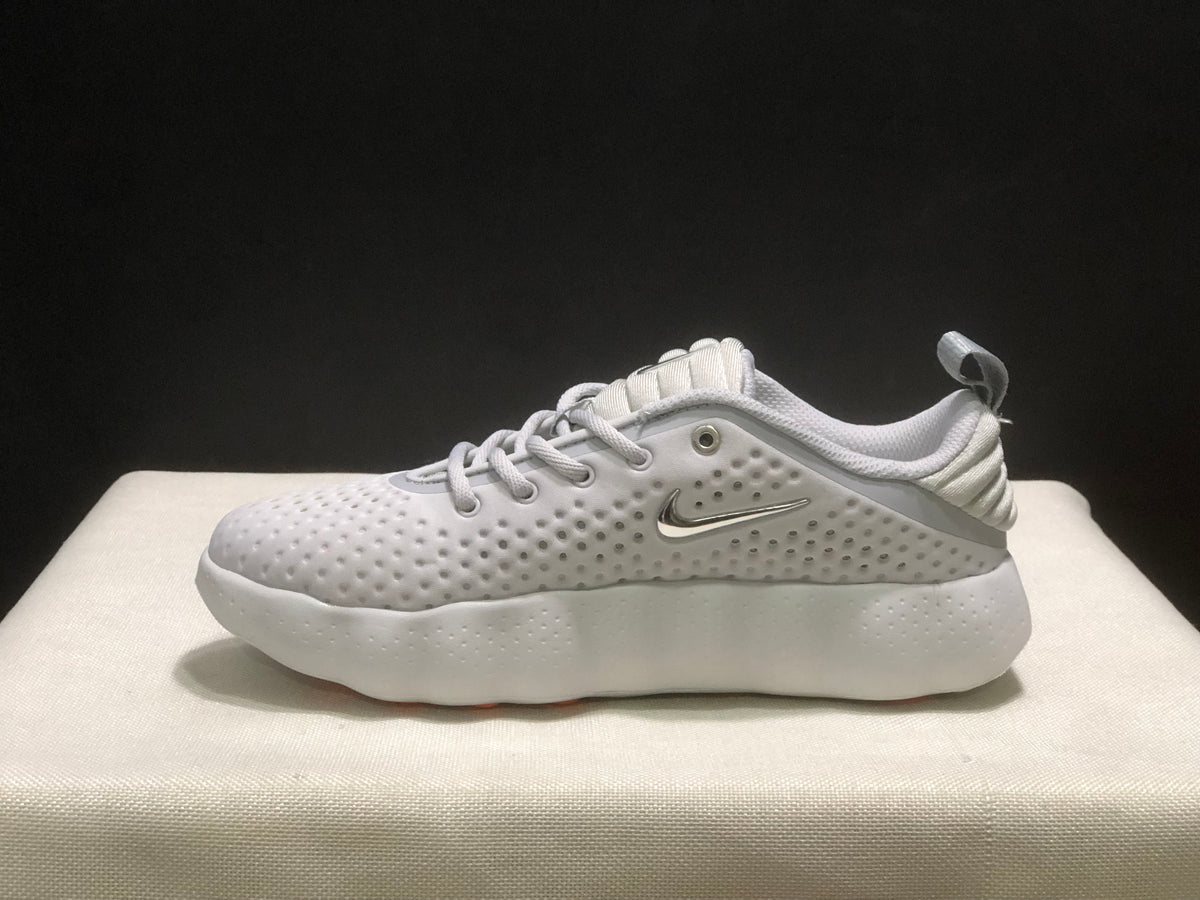 Side profile of a white sneaker showing the metallic-colored side logo, perforated upper and cushioned-looking sole.