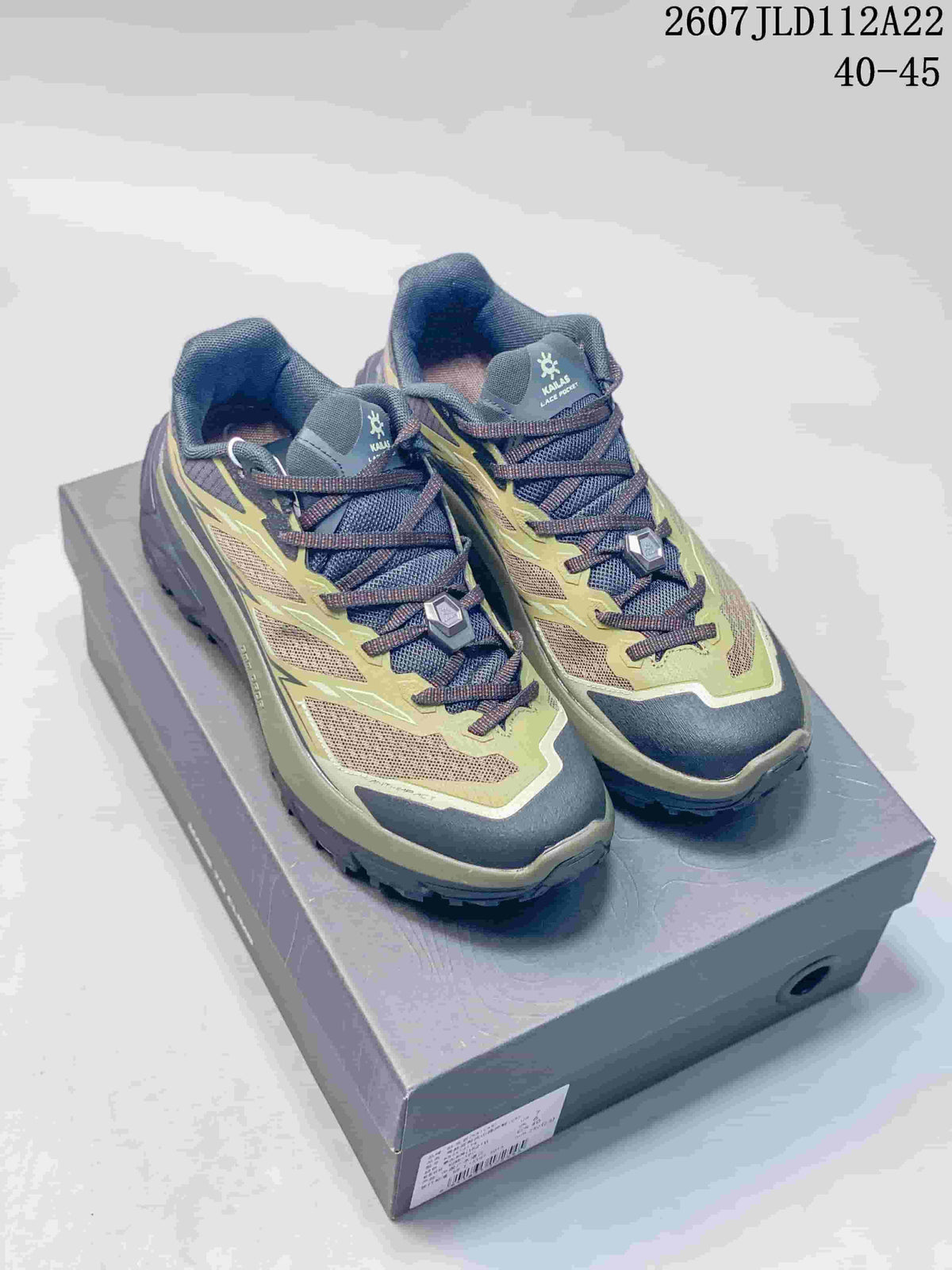 Pair of KAILAS C 4 low-top outdoor shoes in olive, dark navy, and brown, displayed on a shoebox.