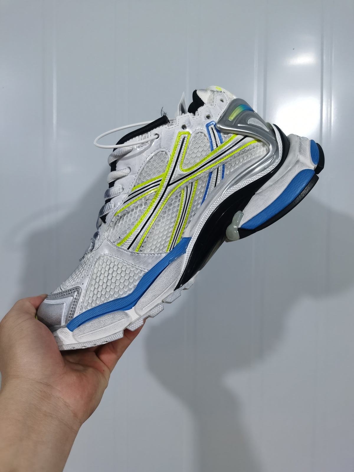 Side view of the white and blue Puma Runner sneaker showing the mesh upper, silver detailing, blue accents, and neon yellow trim.