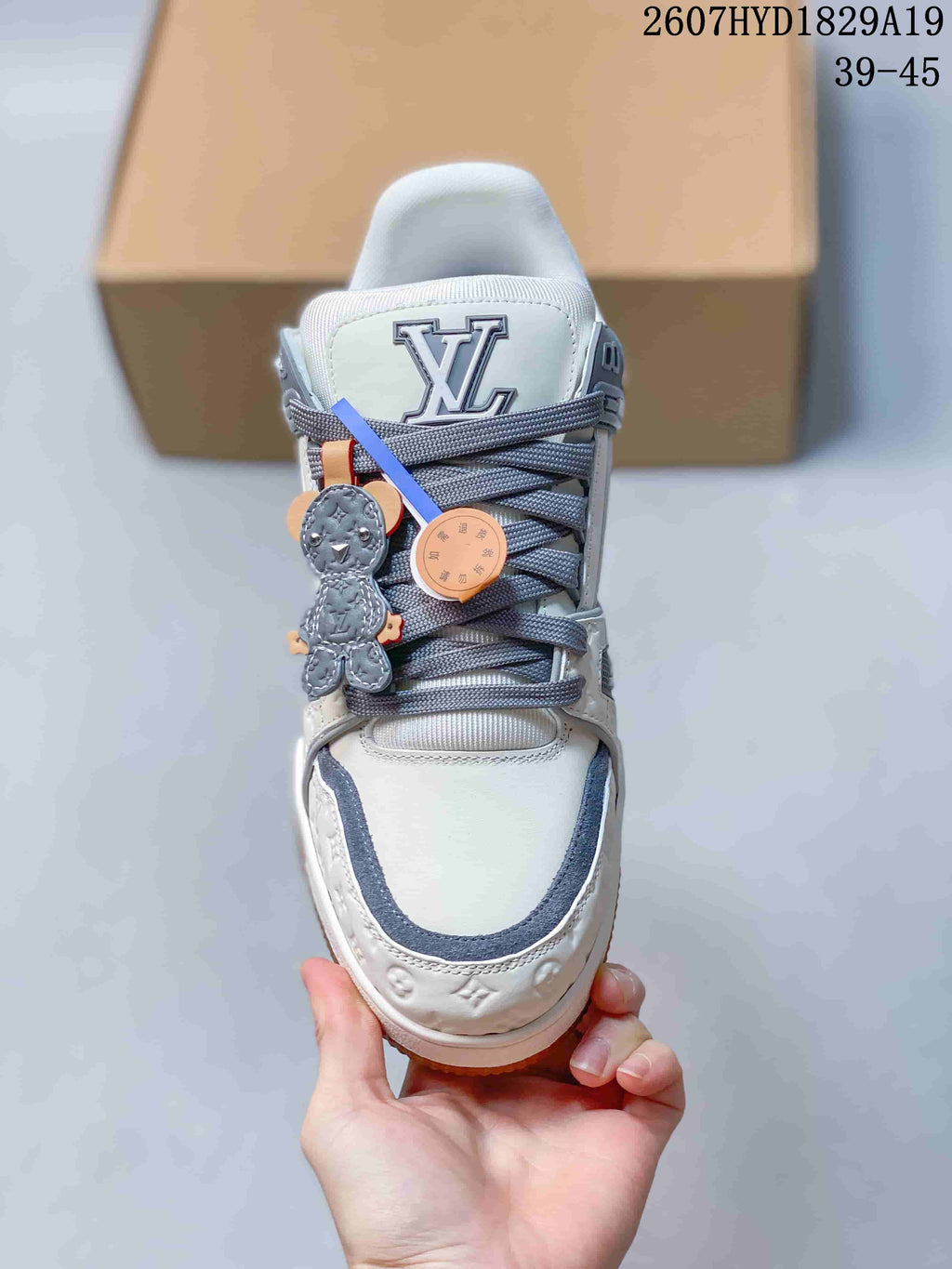 Top view of the sneaker showing the white toe box, gray trim, padded tongue, gray laces, and decorative lace accessories.