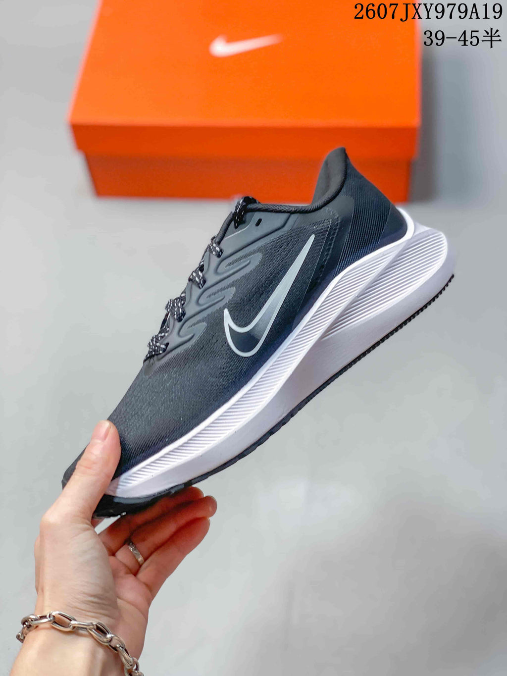 Side view highlighting the dark upper, white side logo, sculpted white midsole, and low-top profile.