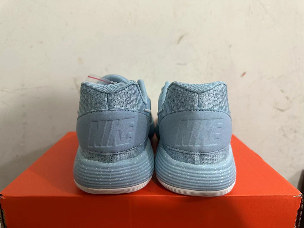Rear view of light blue Nike basketball shoes with ridged soles.