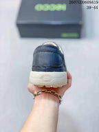 Rear view of the navy sneaker showing the heel panel, contrast sole, and embossed geometric detail.