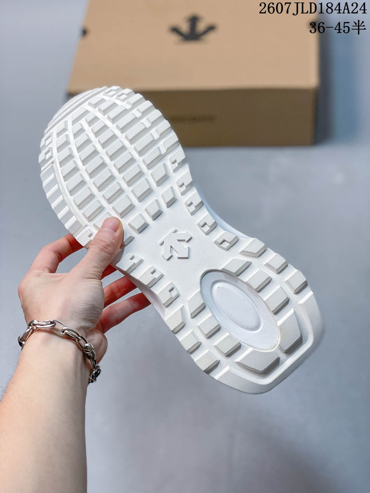 Underside of a white sneaker showing the raised geometric tread pattern and central outsole emblem.