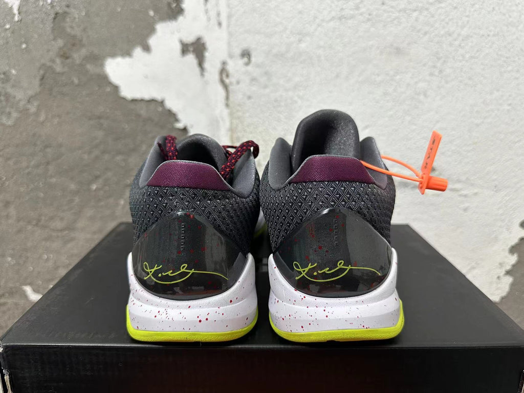 Rear view of black and burgundy Nike basketball shoes with a speckled white midsole and bright yellow-green outsole.