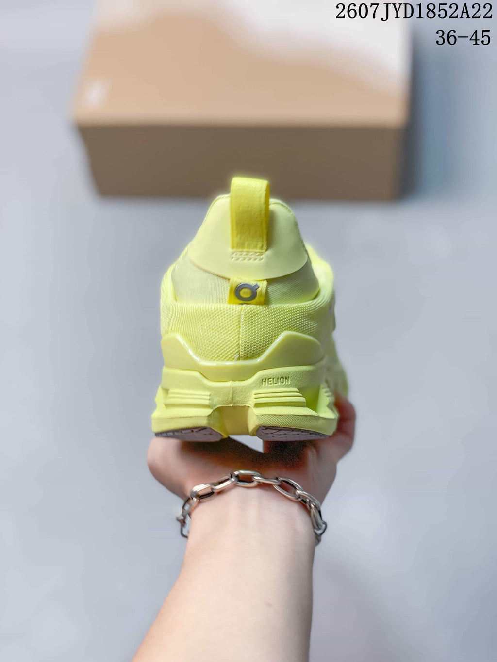 Rear view of the lime yellow sneaker showing the heel pull tab, On branding, and Helion marking on the sole.