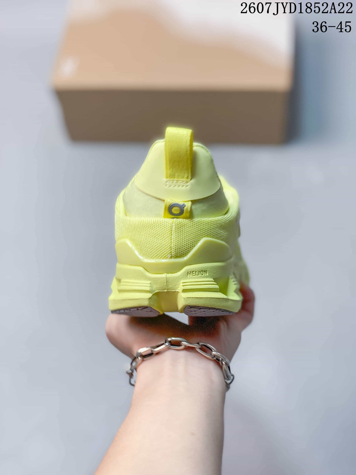 Rear view of the lime yellow sneaker showing the heel pull tab, On branding, and Helion marking on the sole.