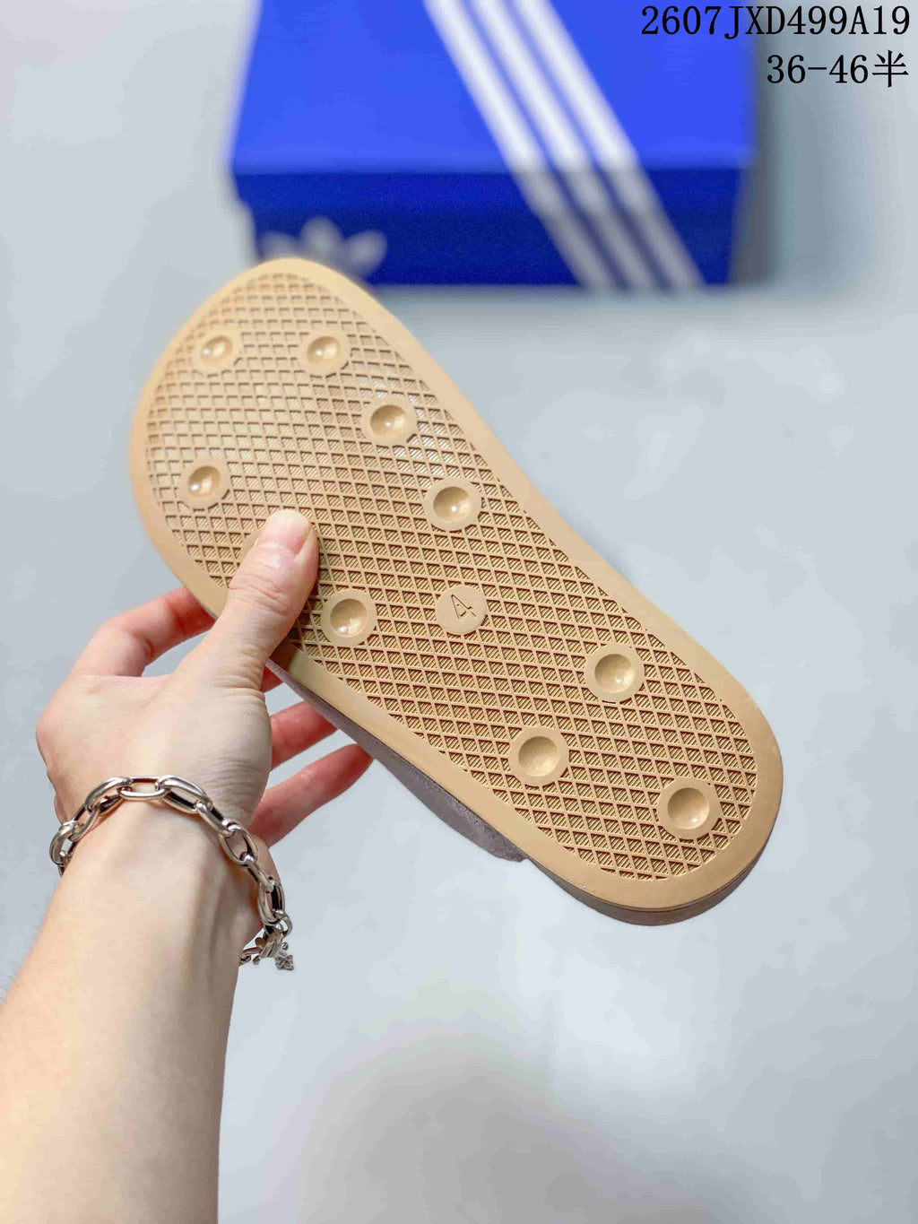 Tan textured outsole of the mule slide, showing a patterned tread and circular traction details.