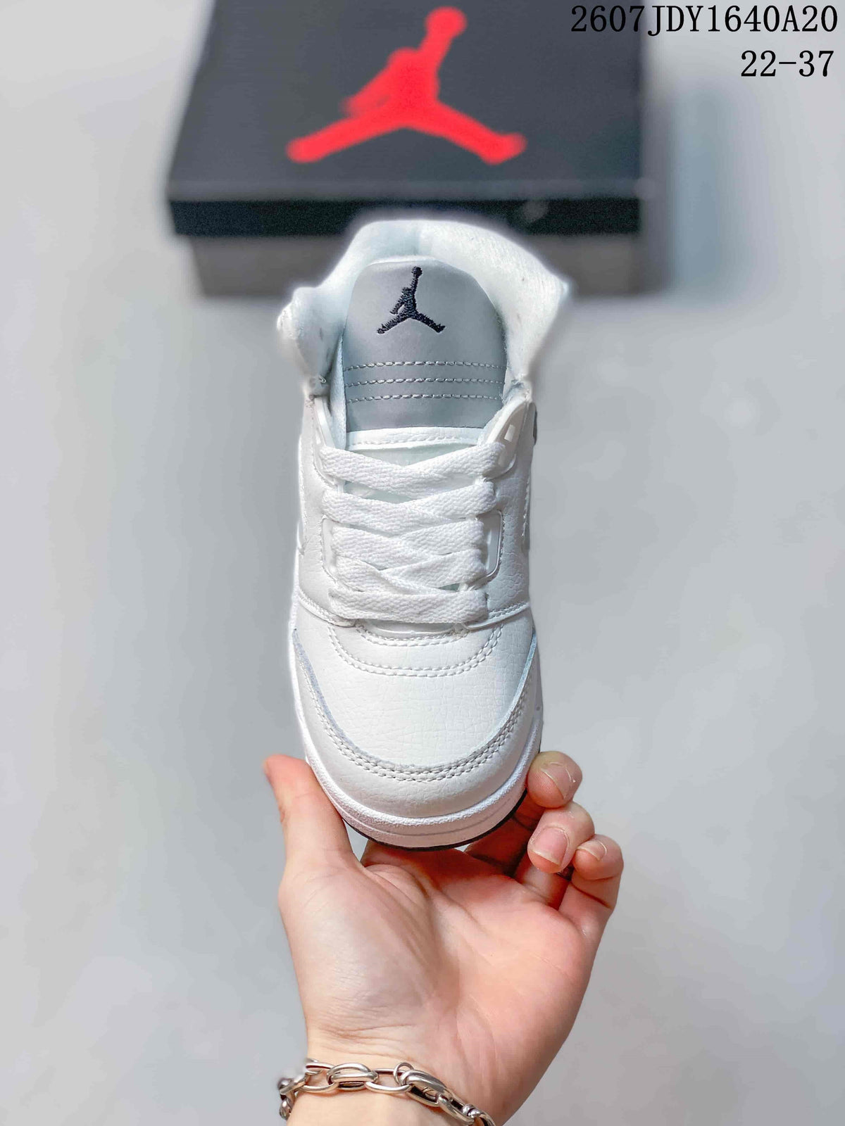 Front view of the white sneaker showing the tongue logo, white laces, and stitched toe-panel details.