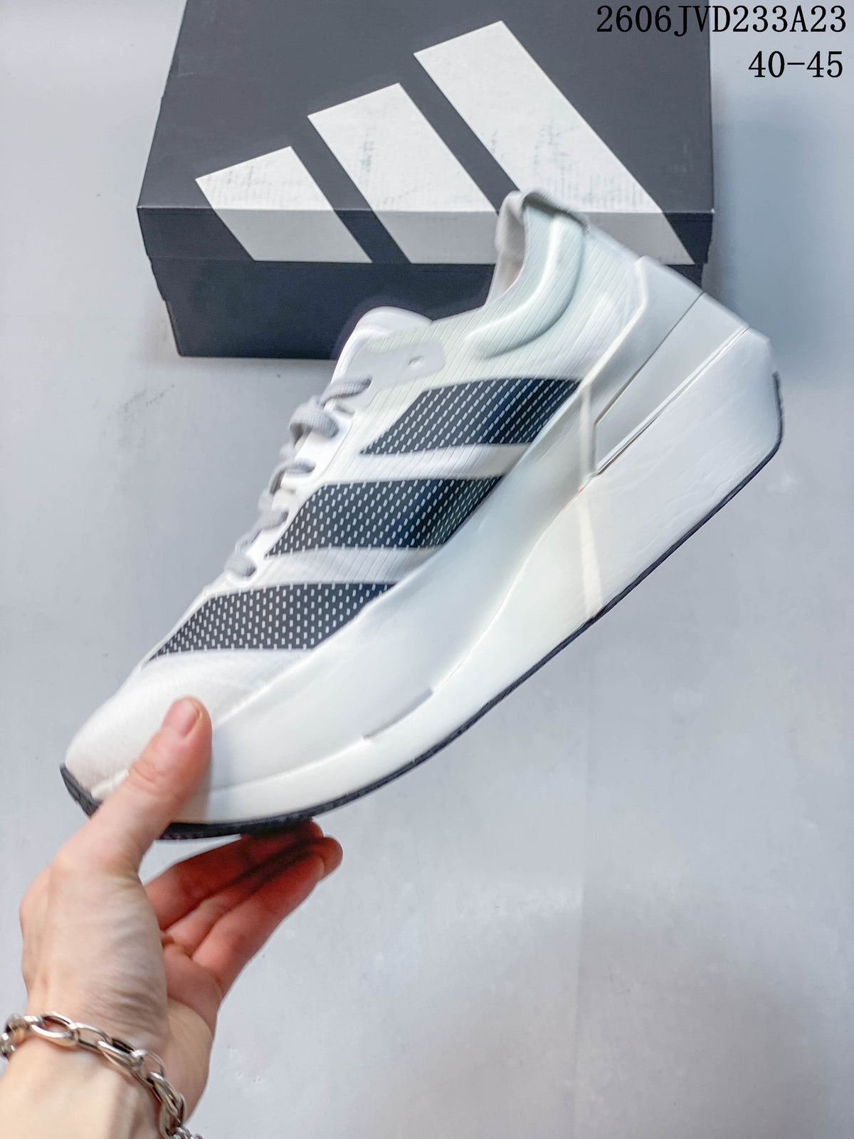 Side view of a white running shoe with navy dotted stripes