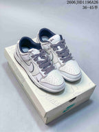White low-top sneakers with dark blue patterned laces, dark lining, and contrasting panel stitching.