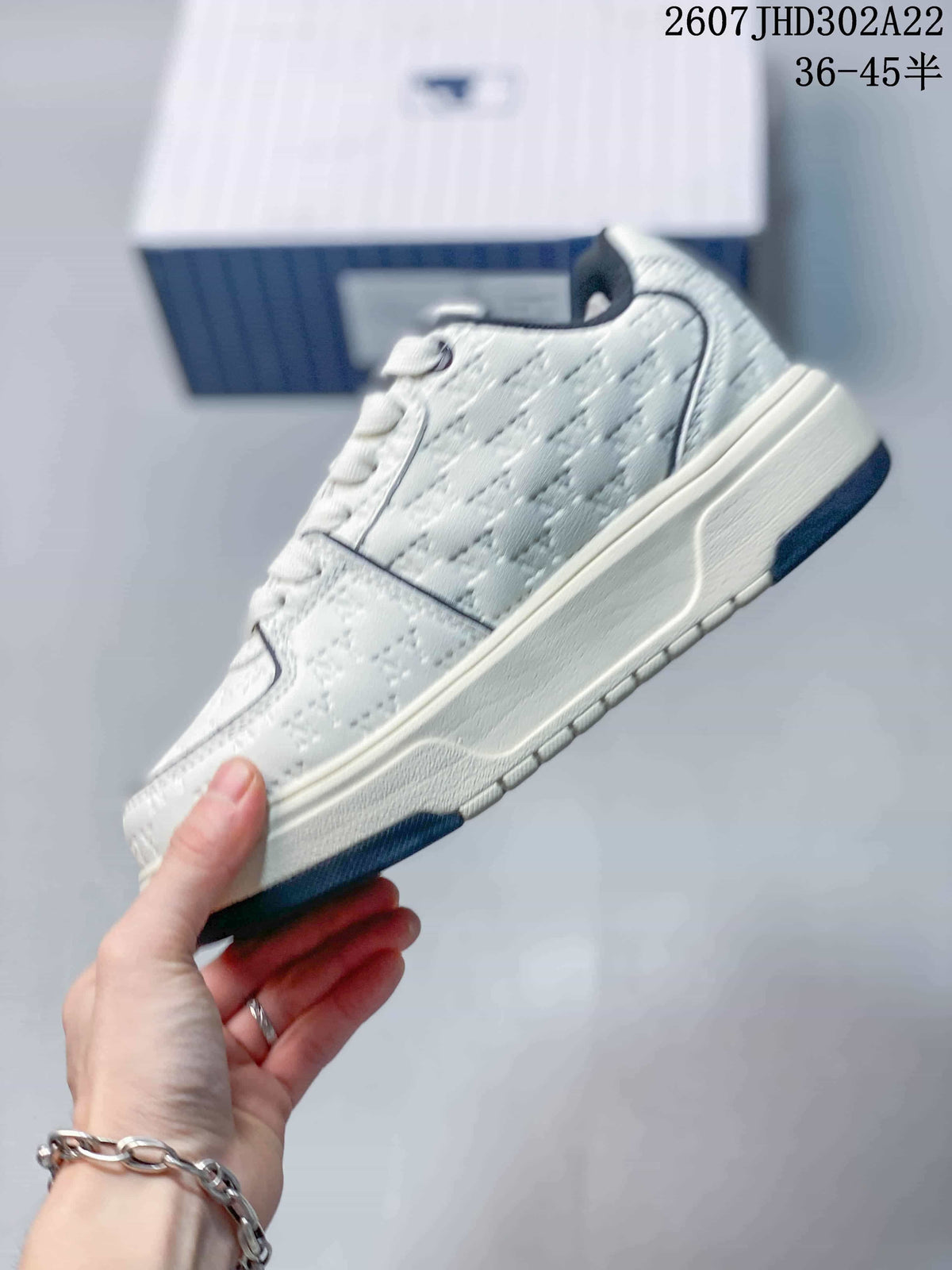 Side view of the white sneaker showing the textured panels, navy trim, lace eyelets, and thick cream-colored sole.