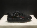 Side view of a black sneaker with orange accents visible through the perforations and a silver-colored side logo.