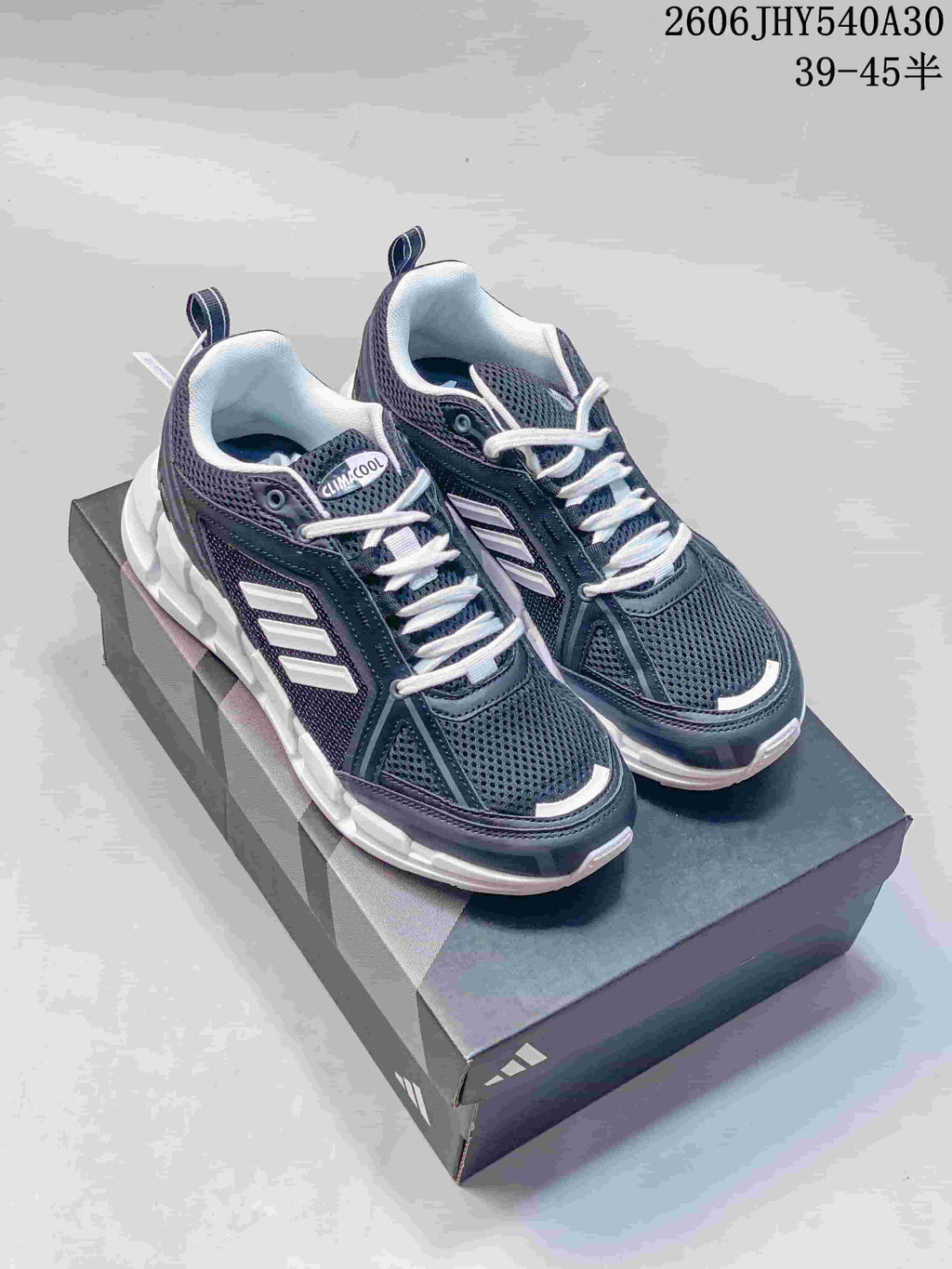 Pair of dark navy and gray Adidas Climacool Ventage low-top shoes with white accents, shown on a box.