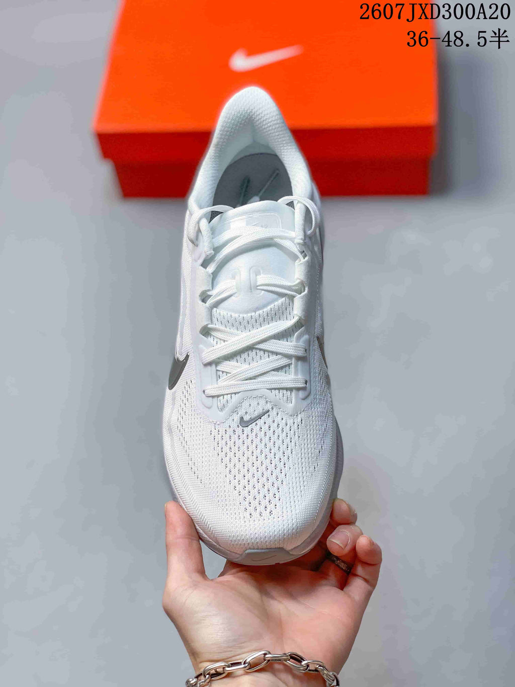 Top view of a white lace-up sneaker showing the perforated-looking toe area, tongue, laces, and small Swoosh detail.