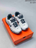Pair of white and black Nike Initiator sneakers displayed on an orange shoebox.