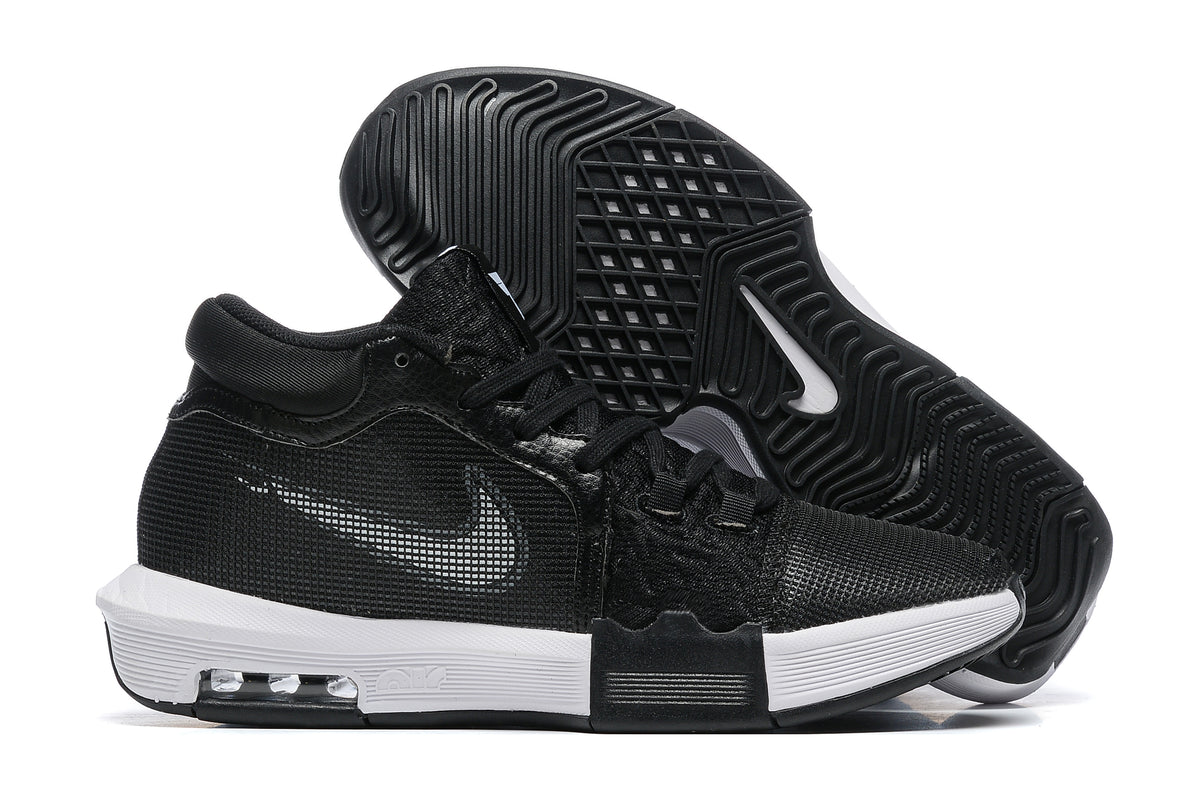 Black low-top basketball shoes with white accents, shown from the side and outsole.