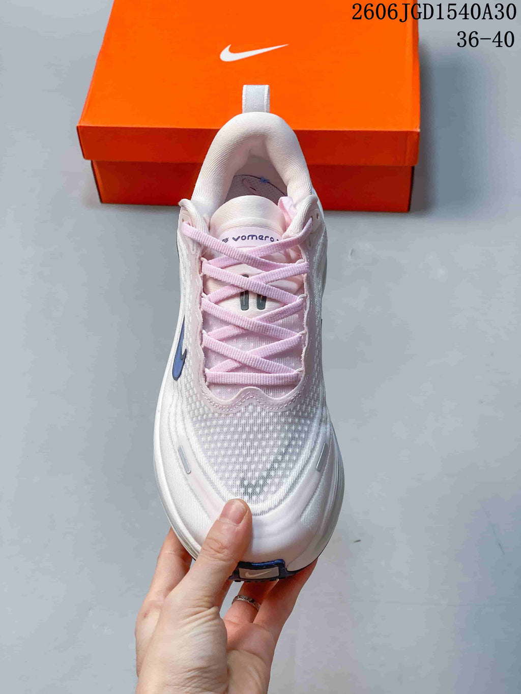 Top view of a Nike Vomero Plus shoe with pale pink laces and a textured white upper.