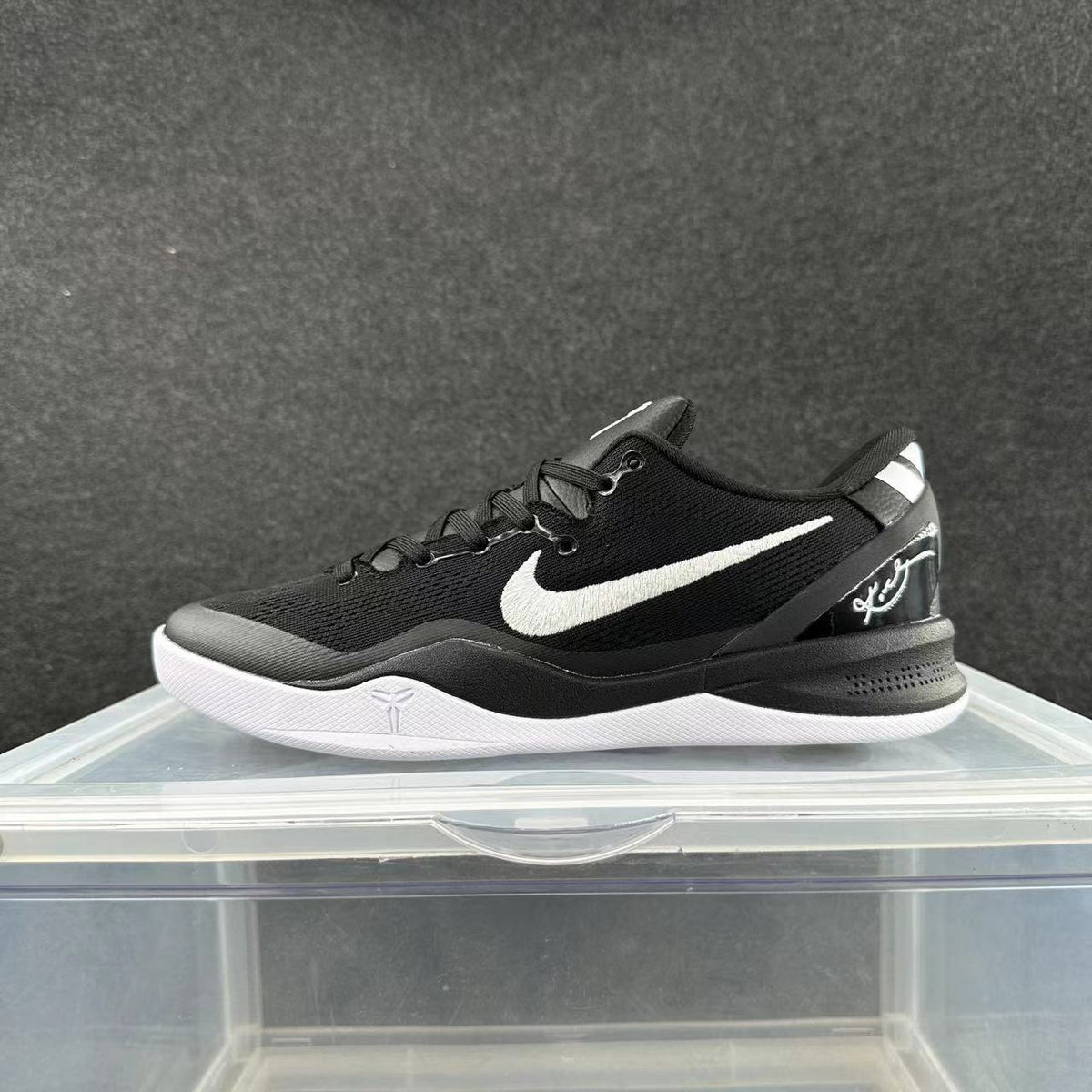 Side view of a black Nike low-top basketball sneaker with white side logo and outsole