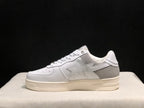 Side view of a single white and gray low-top sneaker with a star side detail and layered outsole.