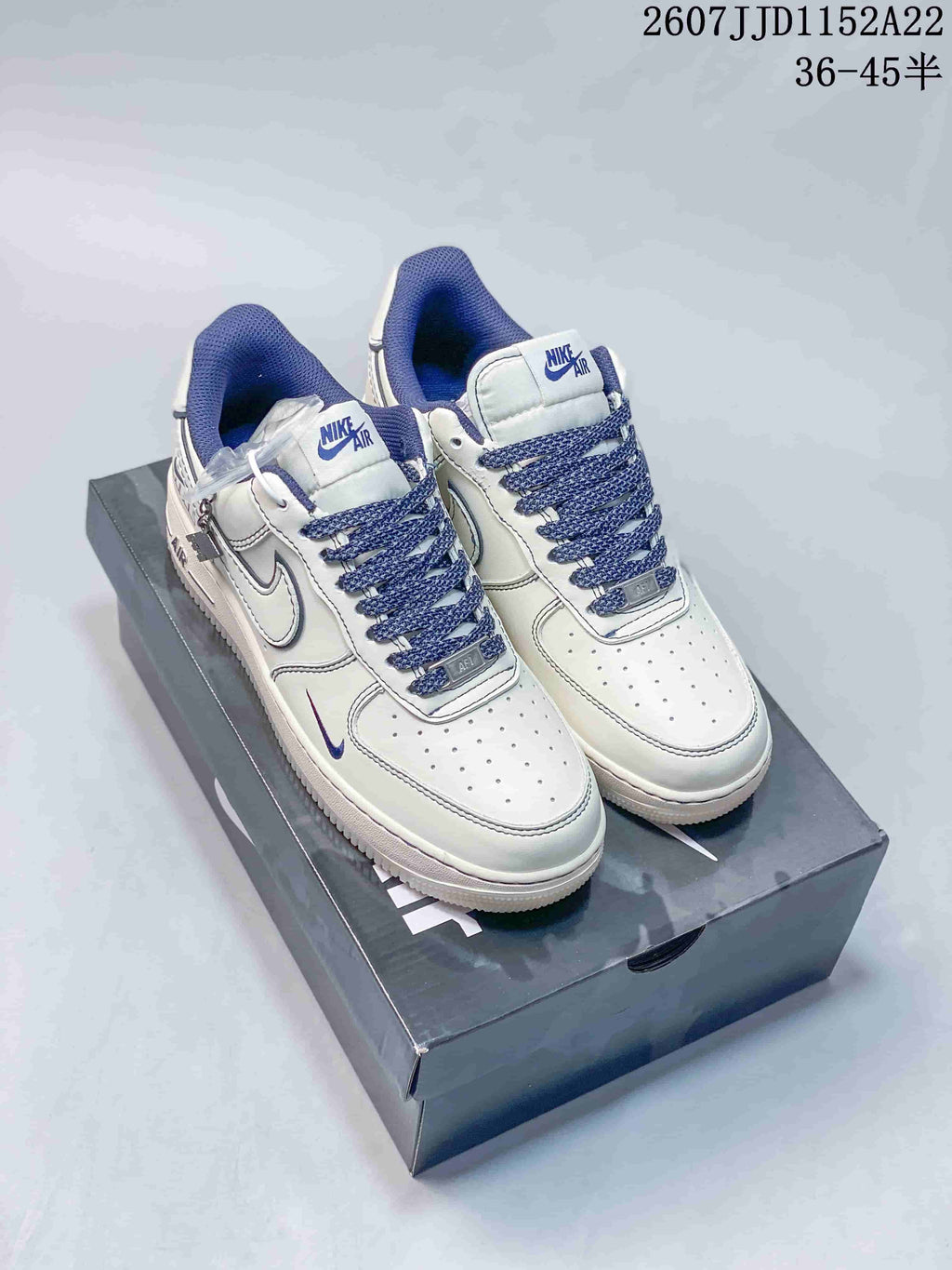 Pair of white and blue Nike Air Force 1 '07 low-top sneakers displayed on a shoebox, with style code and size range text above.