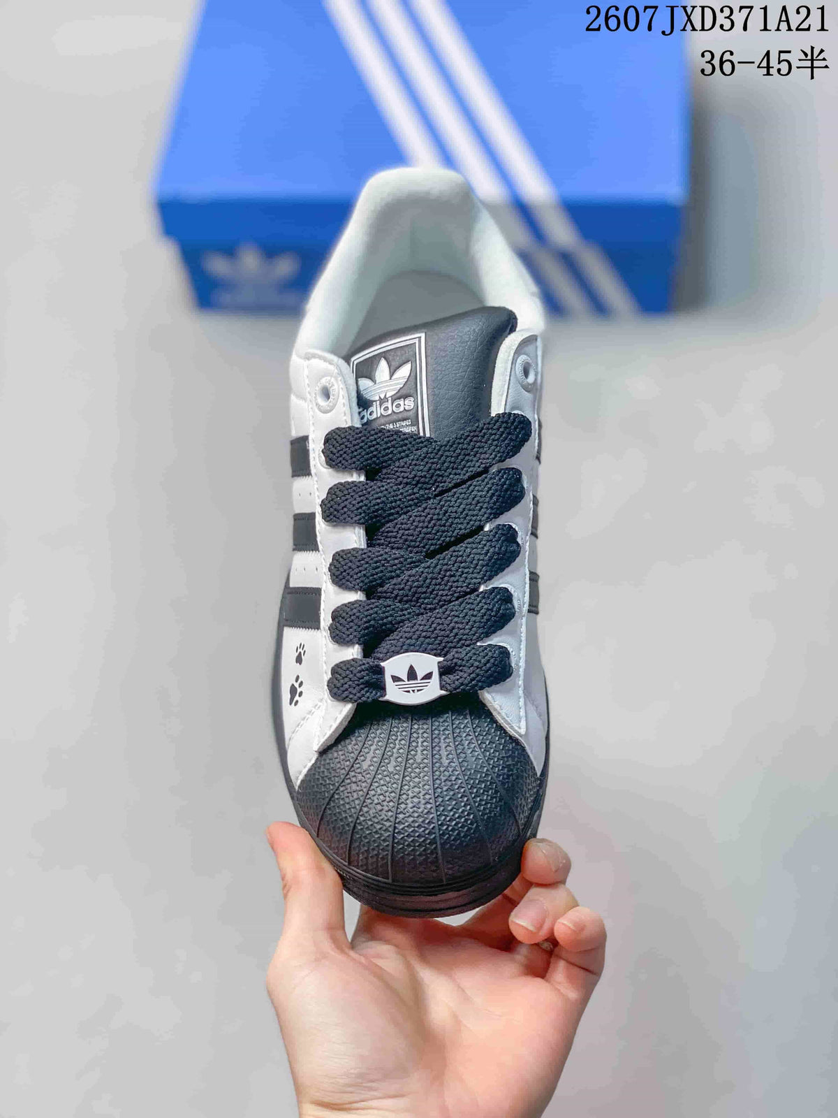 Front view showing the black shell toe, dark laces, Trefoil tongue label, and paw-print details.