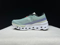 Side view of a pale green On Cloudmonster 2 shoe with purple heel detailing and a sculpted white sole.