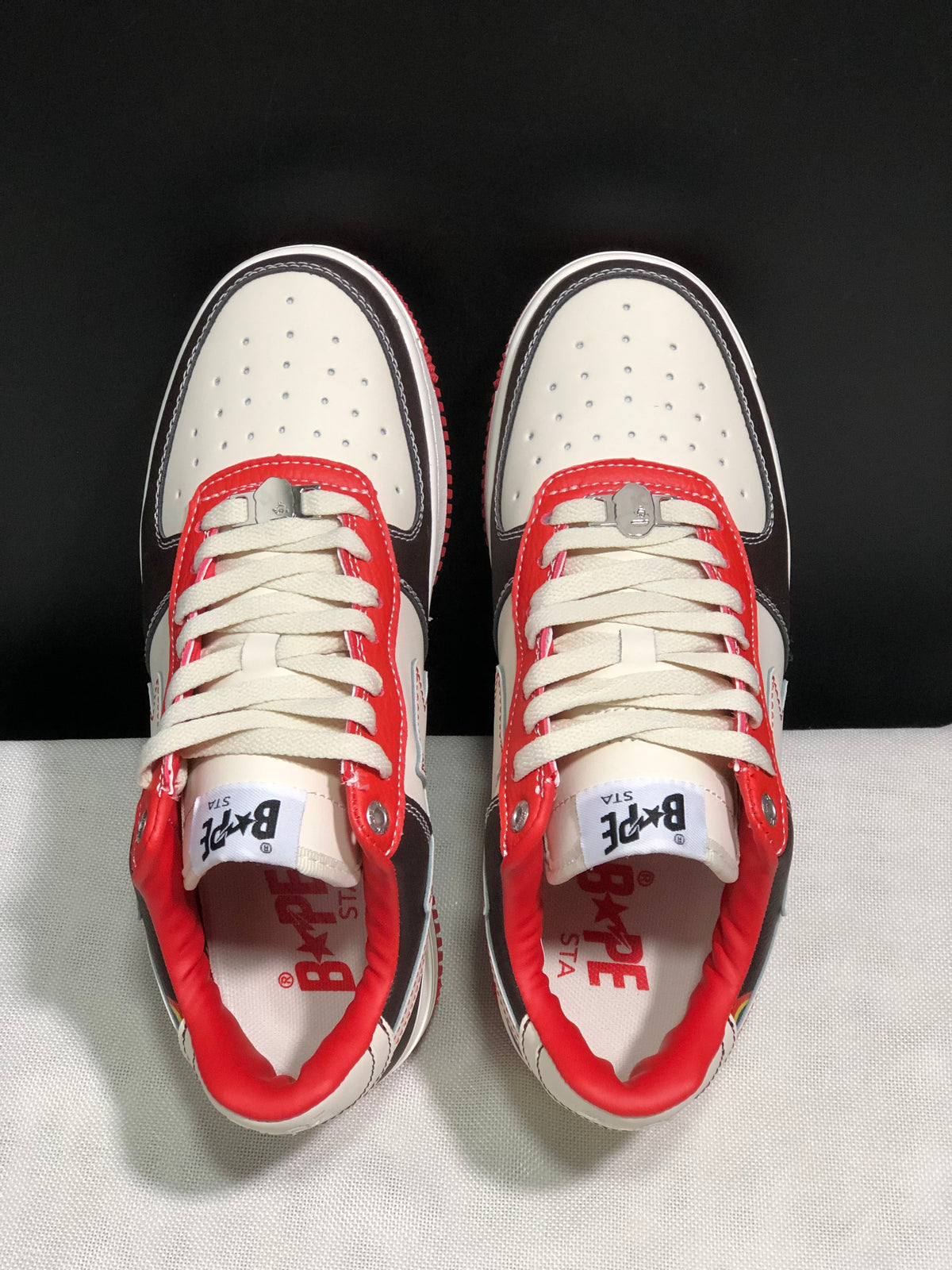 Top-down view showing perforated white toe boxes, cream laces, red lace panels, and branded insoles.