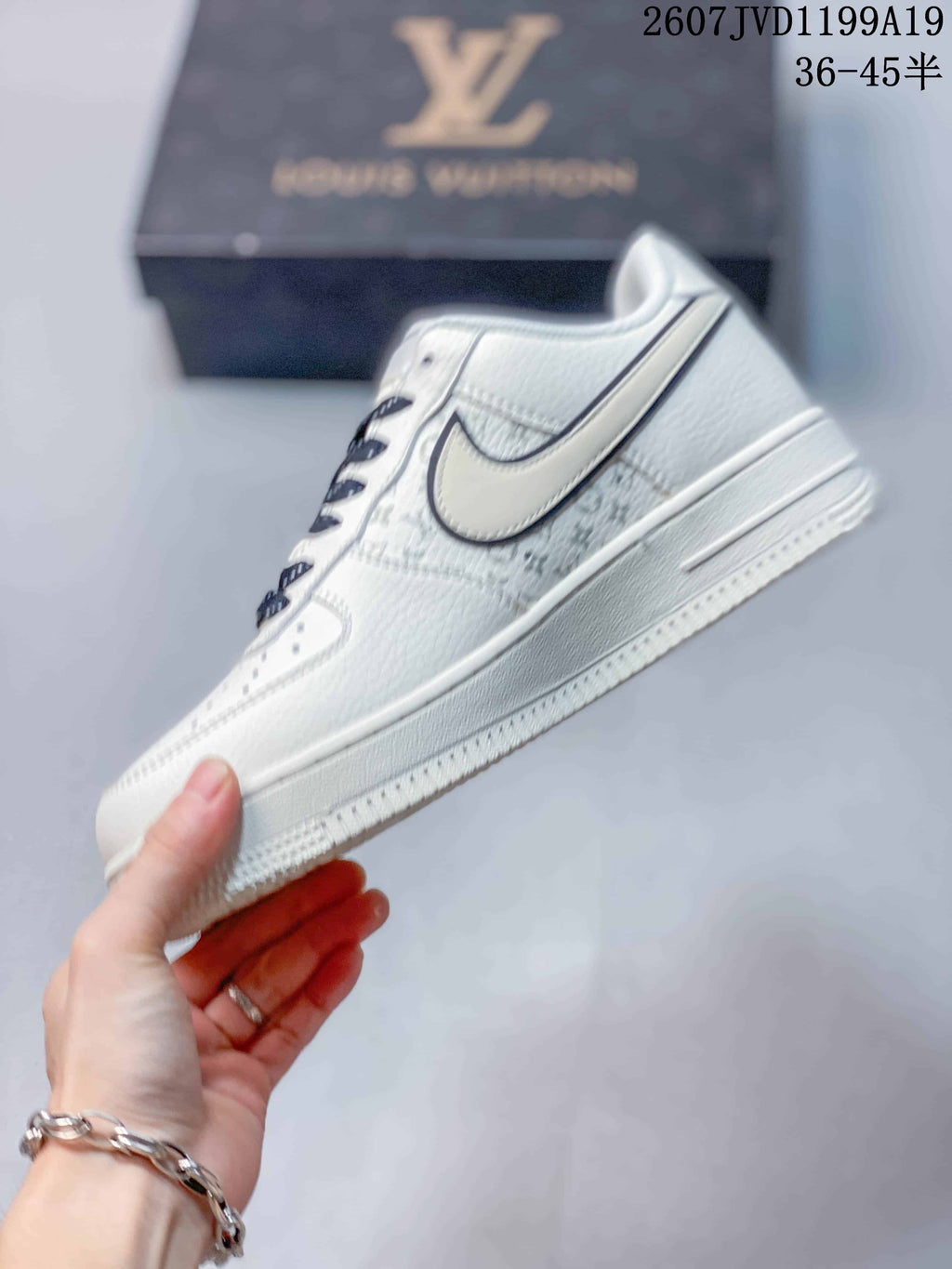 Side view of a white low-top sneaker with an outlined Swoosh and monogram-style side-panel detailing.