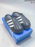 Pair of charcoal adidas adiFOM Superstar mule slides with white stripes, displayed on a blue box