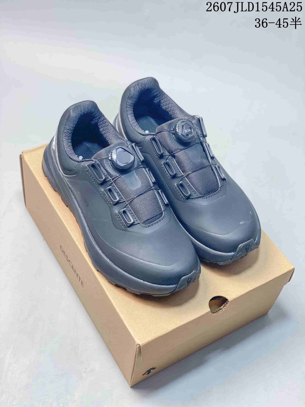 Pair of black Descente low-top sneakers displayed on a Descente shoe box, with source text showing JLD1545A25 and 36–45 half sizes.