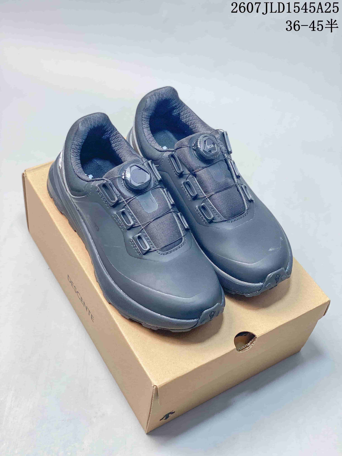 Pair of black Descente low-top sneakers displayed on a Descente shoe box, with source text showing JLD1545A25 and 36–45 half sizes.