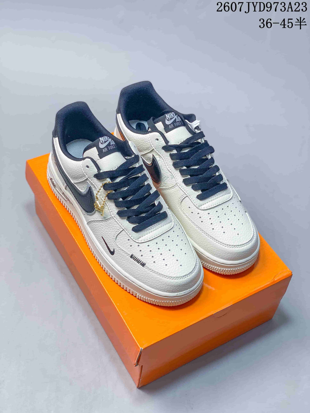Pair of white and navy Nike Air Force 1 '07 sneakers displayed on an orange box; overlay text shows the code 2607TYD973A23 and size range 36–45.5.