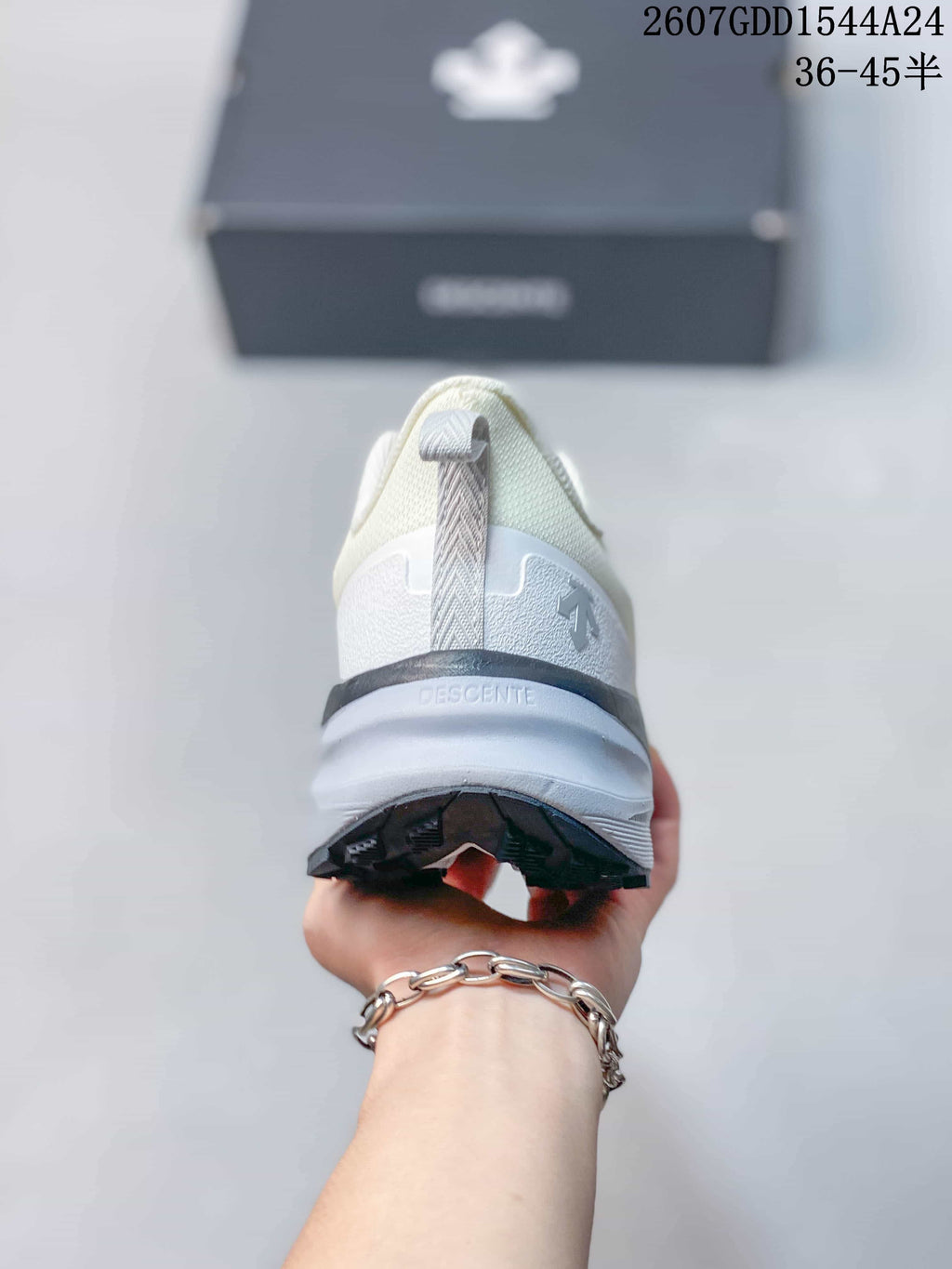 Rear view of the sneaker showing the heel pull tab, layered heel structure, DESCENTE branding, and black outsole edge.