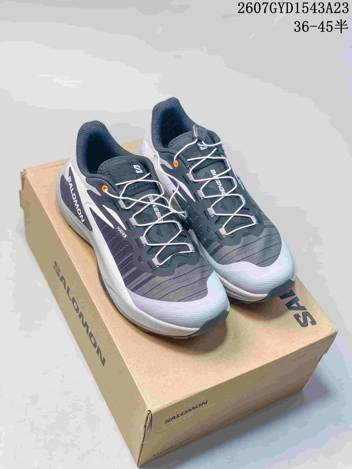 Pair of gray and white Salomon Genesis trail running shoes displayed on a Salomon shoe box.