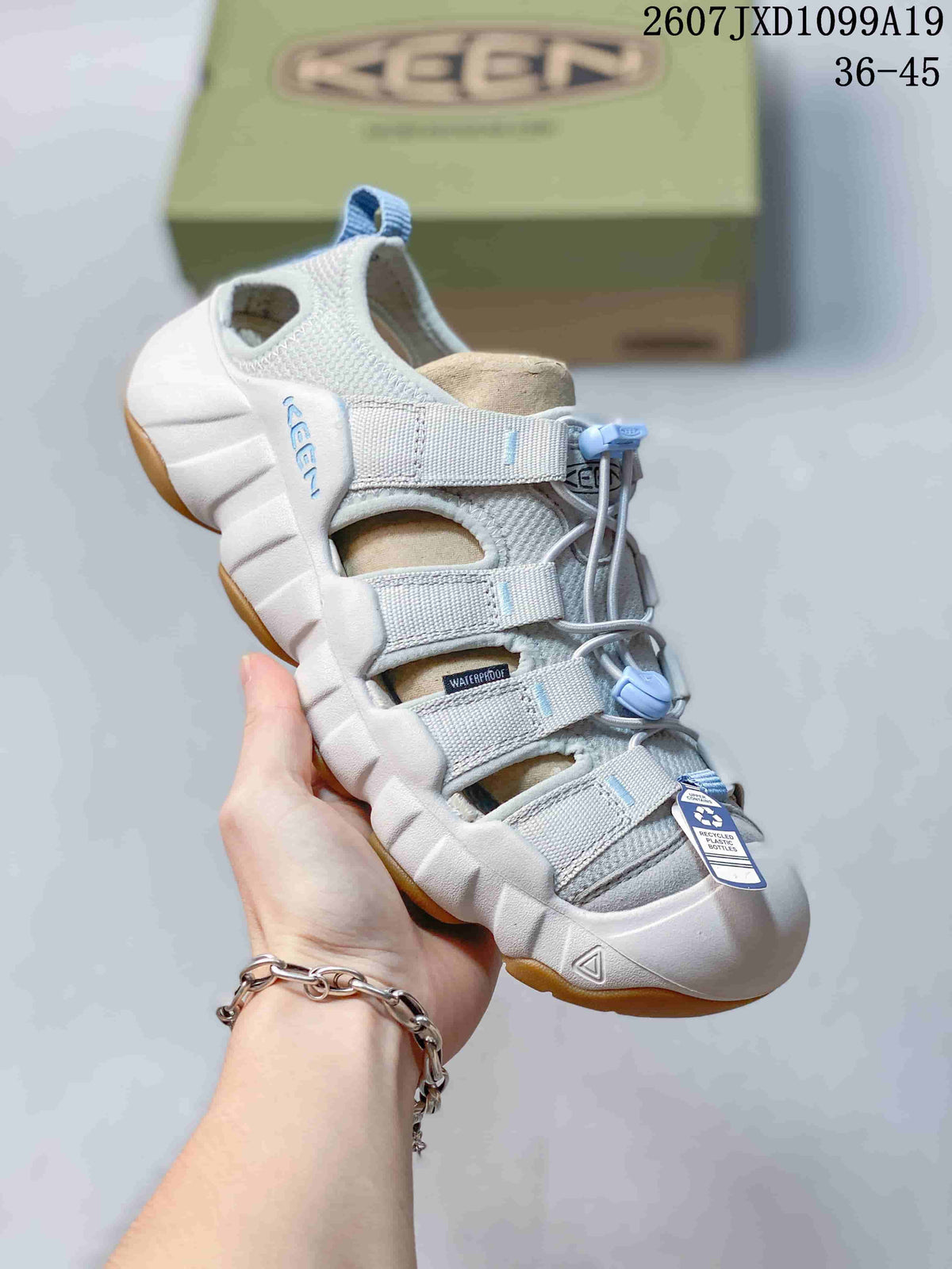 White and light gray Keen sandal with blue quick-lacing hardware, open panels and a tan outsole section; the image includes the size range 36–45.
