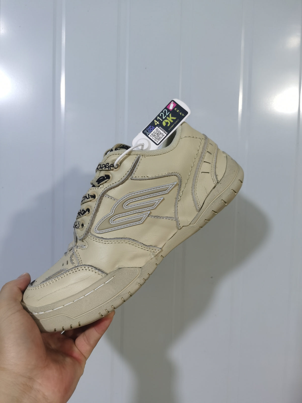 Side and front view of the khaki Balenciaga sneaker showing layered panels, laces, and the raised side logo.
